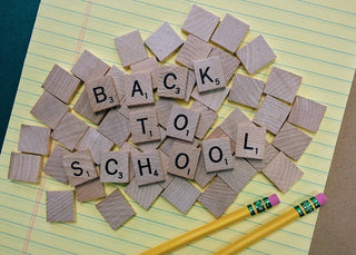 Back to School spelled out in scrabble tiles with pencils and a legal pad.