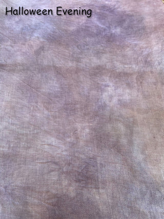 A close-up of a Halloween-themed fabric backdrop with a mottled, distressed texture in shades of dusty purple, gray, and beige. The text 'Halloween Evening' is printed in black at the top left corner.