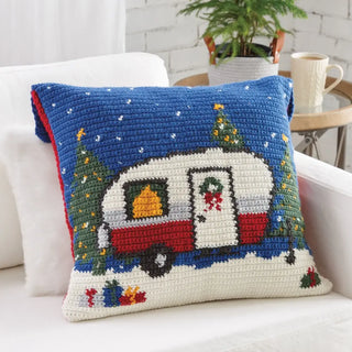 Decorative pillow with a Christmas-themed caravan design on a white couch.