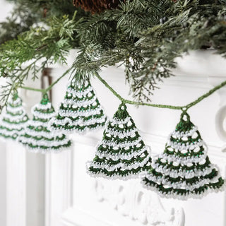 Crocheted Christmas tree ornaments hanging on a branch with a white background