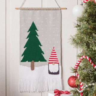 Wall hanging with a Christmas tree and gnome design next to a decorated Christmas tree.