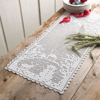 White lace table runner on a wooden table with decorative items.