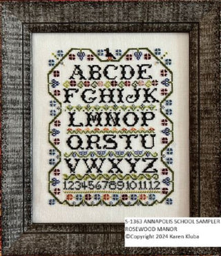 A cross stitch pattern depicting the alphabet from A to Z, arranged in a floral and geometric pattern within a framed design.