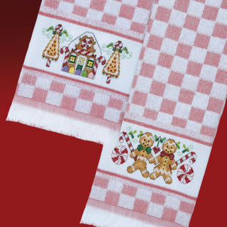Two embroidered towels with gingerbread men and candy cane designs on a red and white checkered background.