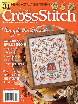 Magazine cover of 'Just CrossStitch' with a cross-stitched piece on an orange background