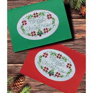 Two Christmas cards with 'Merry Christmas' text on a wooden surface with pine cones and branches.