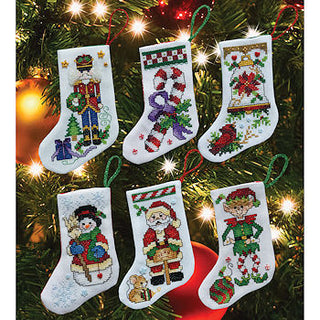 Set of five embroidered Christmas stockings hanging on a decorated tree.