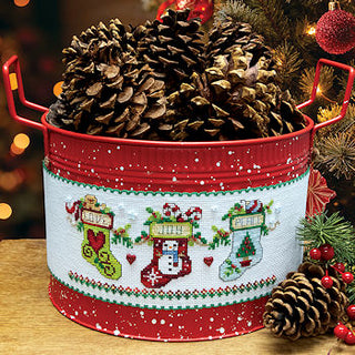 Decorative Christmas tin with pinecones and festive design on a wooden surface.