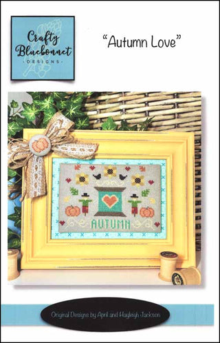 Cross-stitch design with teal thread spool, red heart, sunflowers, pumpkins, and scarecrows — autumn folk art by Crafty Bluebonnet Designs.
