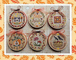 Set of six cross-stitched autumn-themed hoop ornaments on a textured fabric background.