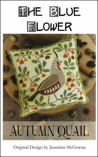 Decorative pillow with autumn quail design on a wooden surface with acorns.