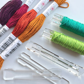 Colorful embroidery threads and bobbin pegs on a white background
