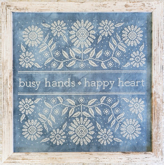 Decorative wall art with floral patterns and 'busy hands happy heart' text on a blue background.