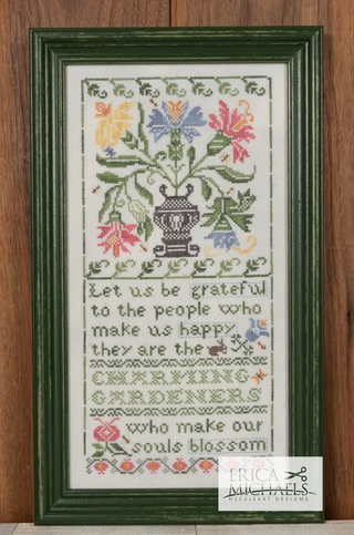 Framed cross-stitched piece with floral design and text on a wooden background