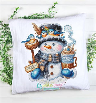 Decorative pillow with a snowman design holding a cup and surrounded by birds, on a white background.