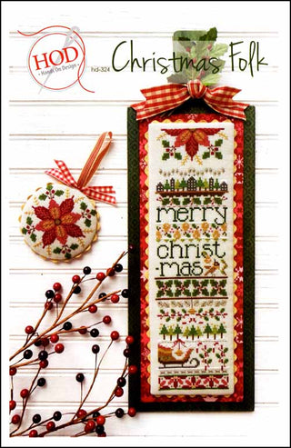 Vertical Christmas-themed cross-stitch sampler with poinsettias, trees, hearts, animals, and the words “Merry Christmas,” finished as a banner with a matching poinsettia ornament, styled with greenery and ribbon.