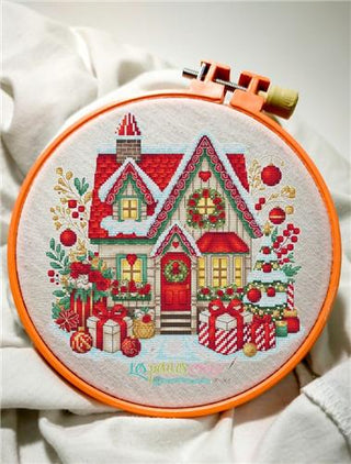 Embroidery hoop with a Christmas-themed house design on fabric.