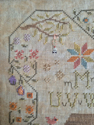 Close-up of a cross-stitched piece with floral patterns Alphabet.