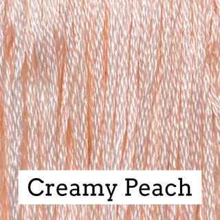 Close-up of peach-colored embroidery thread with a white label at the bottom reading 'Creamy Peach'.