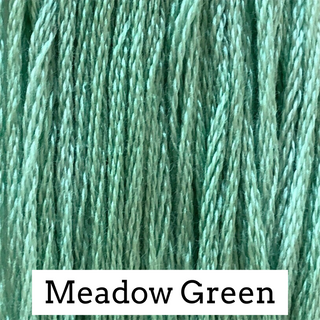 Close-up of mint green embroidery floss threads with a white label at the bottom reading 'Meadow Green'.