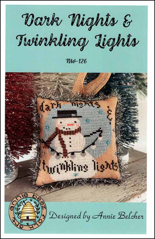 Cross-stitched snowman ornament with 'Dark Nights & Twinkling Lights' text, featuring Annie Beez logo.