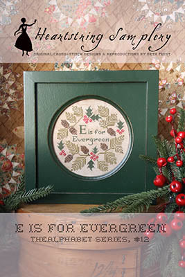 Framed cross stitch design featuring the letter E surrounded by evergreen branches, berries, and floral accents, stitched in soft greens and reds, E Is For Evergreen by Heartstring Samplery.