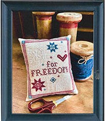 Cross-stitched pillow with 'For Freedom' text, surrounded by spools of thread and scissors.