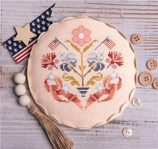 Cross-stitched floral design with decorative elements on a rustic wooden background.