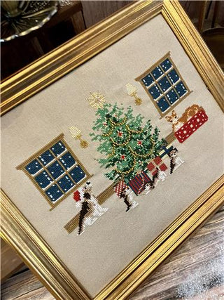 Framed cross-stitched picture of a Christmas scene with a tree and stockings.
