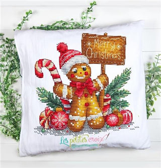 Cross-stitched gingerbread man pillow with Christmas elements on a white background