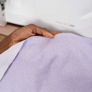 Person using a sewing machine to sew a purple fabric