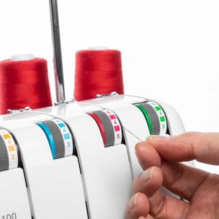 Thread tension dial on a overlock machine with red thread and a hand adjusting the thread.