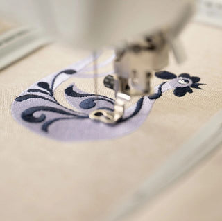 Close-up of a sewing machine needle stitching floral patterns on fabric.