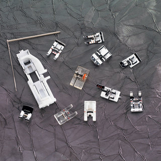 Collection of sewing machine attachments on a textured gray surface