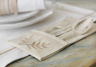 Beige napkin with leaf design using HUSQVARNA® VIKING® EMERALD™ 116 Sewing Machine on a wooden table with cutlery 