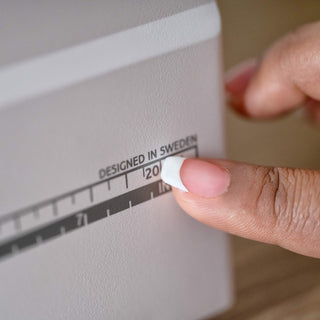 Hand adjusting a white appliance with 'Designed in Sweden' text