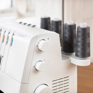 White sewing machine with spools of thread on a wooden surface