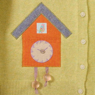 Yellow cardigan with a cuckoo clock patch on a green background