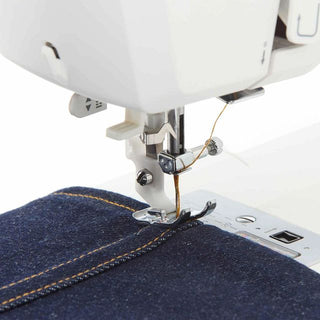 Sewing machine stitching blue denim fabric on a white background