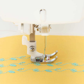 Sewing machine needle on yellow fabric with embroidery design