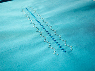 Close-up of a blue embroidered design on turquoise fabric