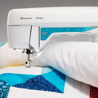 Husqvarna Viking sewing machine on a quilt with colorful patterns