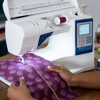 Person using a sewing machine with purple fabric