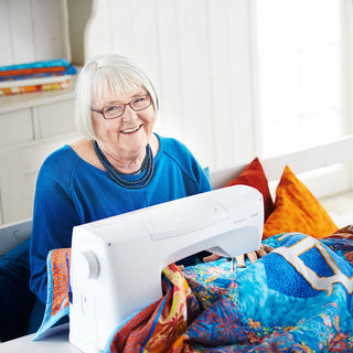 Woman using a sewing machine with colorful fabric in a bright room