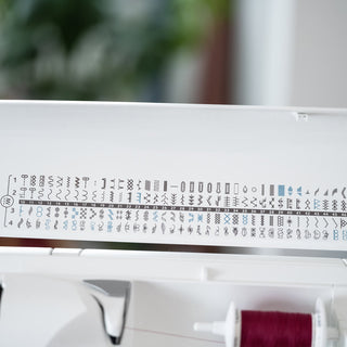 Sewing machine needle plate with various stitch patterns on a blurred background