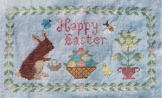 Cross-stitched Easter design with bunny, eggs, and flowers on fabric.