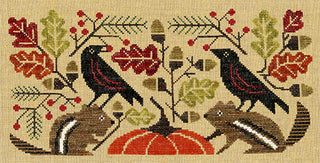 A cross-stitch pattern design featuring two black birds, squirrels, a pumpkin, acorns, and autumn leaves on a beige fabric background.