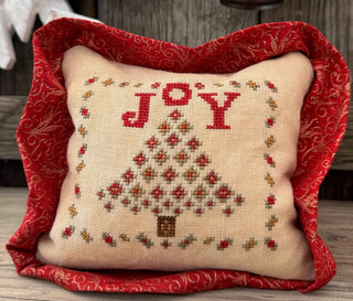 Decorative pillow with 'JOY' and Christmas tree design on a red border.