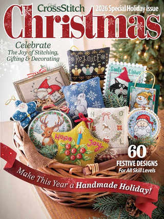 Cover of CrossStitch Christmas 2026 Special Holiday Issue magazine, featuring a wicker basket filled with colorful embroidered holiday ornaments, tags, and fabric pieces, with a Christmas tree in the background.