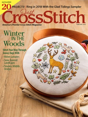 Cover of 'Just CrossStitch' magazine featuring a cross-stitched design with a deer and winter elements.